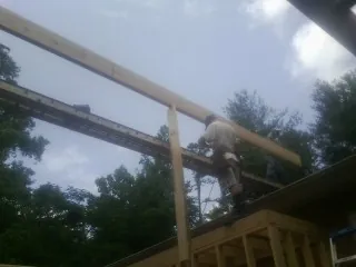 Carpenter setting a ridge beam over a new addition frame — Ice Dam Removal by Roofing Brothers in Saint Anne