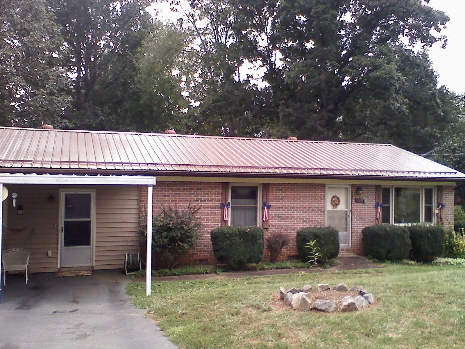 Bronze metal roof and carport on a brick ranch home — Roof Repair work by our crew in Saint Anne