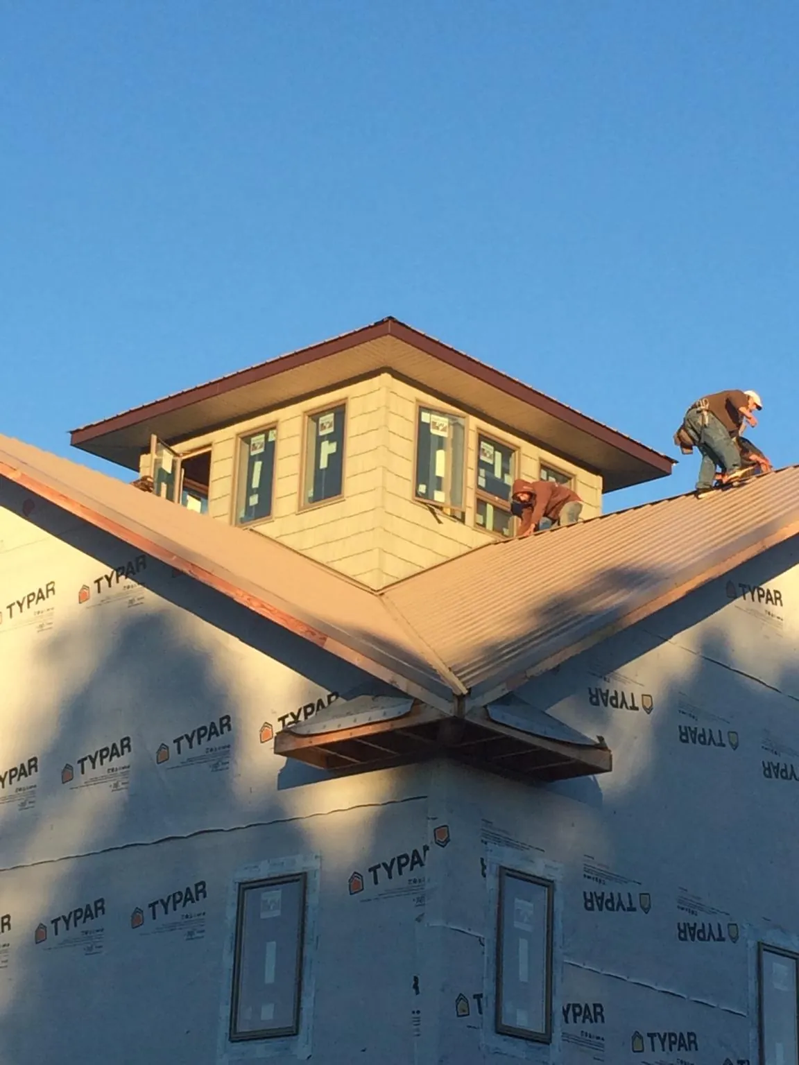Roofers working around a rooftop cupola on a new metal roof at sunset — Roof Waterproofing in Saint Anne by Roofing Brothers